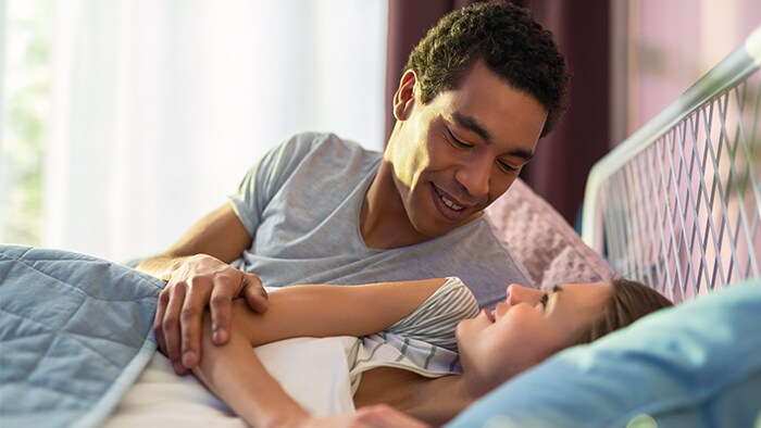 Couple laying on bed smiling to each other